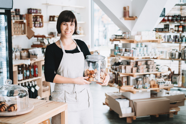 Smiling woman in a local shop holding a glass jar of cookies